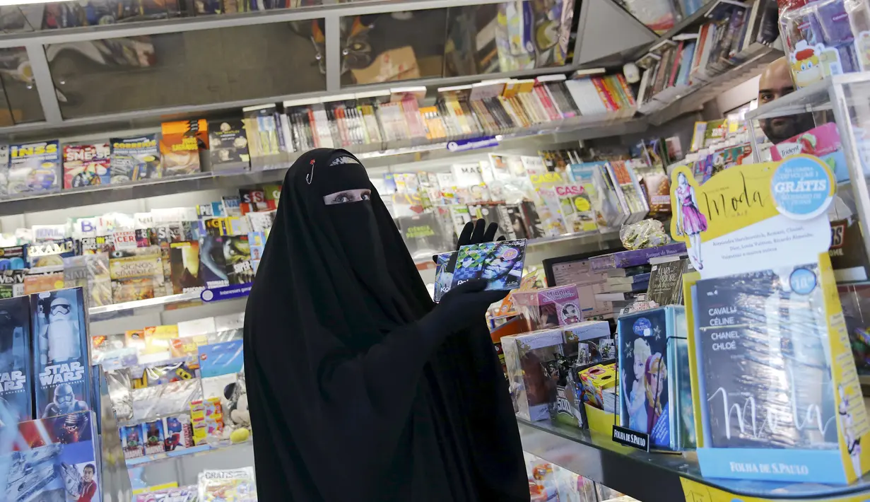 Gisele Marie memilih CD musik disebuah toko usai latihan sebuah studio, Sao Paulo, Brasill (15/9/2015). Banyak orang disekitarnya terkejut melihat seorang wanita Muslim yang menggunakan Burka memainkan musik metal. (REUTERS/Nacho Doce)