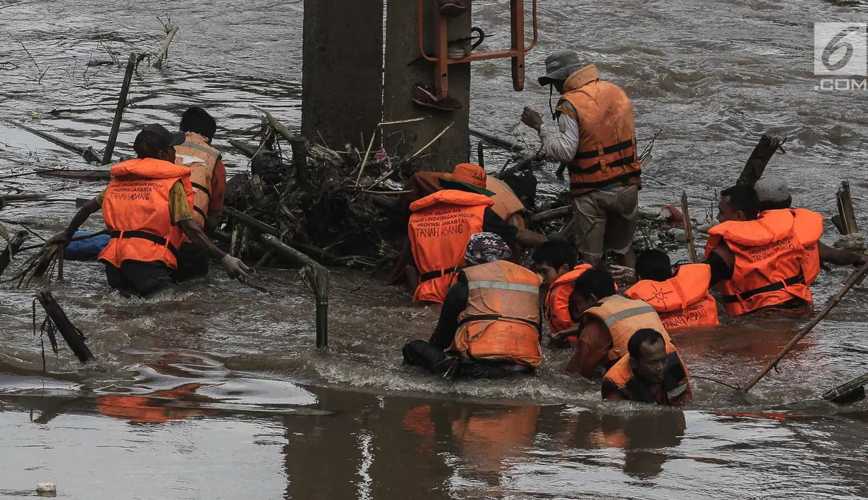 Sejumlah pasukan oranye berjibaku membersihkan sampah batang kayu dan bambu yang tersangkut di aliran sungai Ciliwung di kawasan Sudirman, Jakarta, Jumat (9/2). (Liputan6.com/Faizal Fanani)