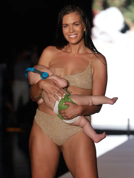 Model Mara Martin berpose di atas runway sambil menyusui bayinya selama Miami Swim Week 2018 di Florida, Minggu (15/8). Sorak sorai penonton mengiringi aksi Mara saat memperagakan koleksi bikini terbaru untuk musim panas 2018. (AP/Lynne Sladky)