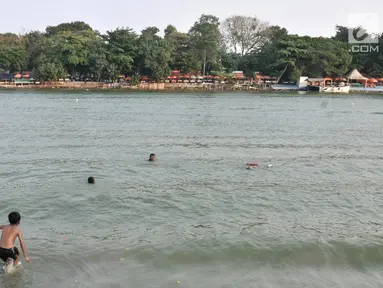 Anak-anak berenang di Danau Sunter, Jakarta, Selasa (23/7/2019). Minimnya fasilitas bermain yang layak dan murah membuat anak-anak nekat berenang di Danau Sunter. (merdeka.com/Iqbal Nugroho)