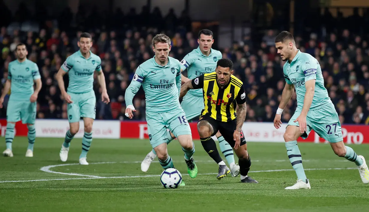 Penyerang Watford, Andre Grey berebut bola dengan  pemain Arsenal, Nacho Monreal dan Konstantinos Mavropanos dalam laga pekan ke-34 Premier League 2018-19 di Vicarage Road, Senin (15/4). Arsenal sukses mengalahkan tuan rumah Watford dengan skor tipis 1-0. (REUTERS/David Klein)