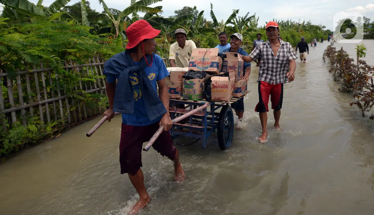 Warga berjalan melintasi banjir di Desa Sindangsari, Kabupaten Bekasi, Jawa Barat, Rabu (24/2/2021). Tim Tanggap Bencana Land Rover Club Indonesia (LRCI) melakukan drop logistik dan mengevakuasi warga yang sakit di Desa Sindangsari. (merdeka.com/Imam Buhori)