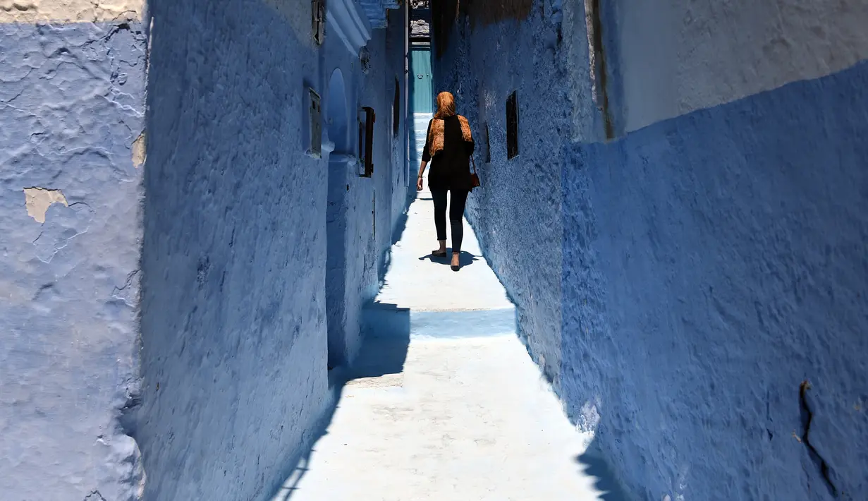 Seorang wanita berjalan di sepanjang gang kecil, Kota Chefchaouen, Maroko, (1/5).Maroko termasuk negara yang bebas visa bagi turis Indonesia membuat Maroko jadi pilihan tepat ketika kamu ingin melakoni travel dengan bugdet minim. (FADEL SENNA / AFP)