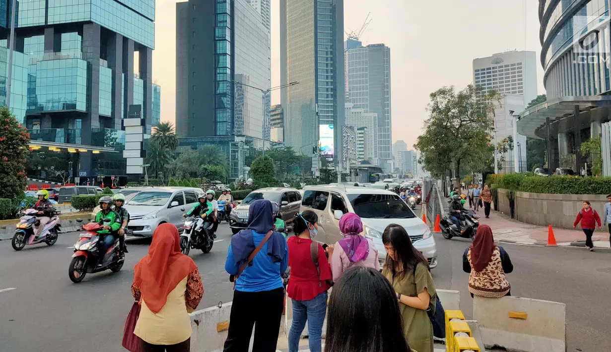 Warga menunggu angkutan umum di tepi Jalan Jenderal Sudirman, Jakarta, Senin (8/7/2019). Tidak adanya halte menyebabkan warga terpaksa menunggu angkutan umum di tempat seadanya. (Liputan6.com/Immanuel Antonius)