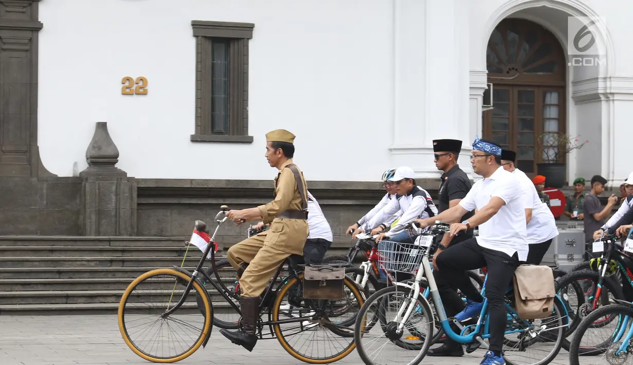 Presiden Joko Widodo atau Jokowi (tengah) didampingi Gubernur Jawa Barat Ridwan Kamil (kanan) saat mengikuti Bandung Lautan Sepeda, Sabtu (10/11). Kegiatan ini diikuti oleh anggota TNI dan Polri serta masyarakat Kota Bandung. (Liputan6.com/Angga Yuniar)