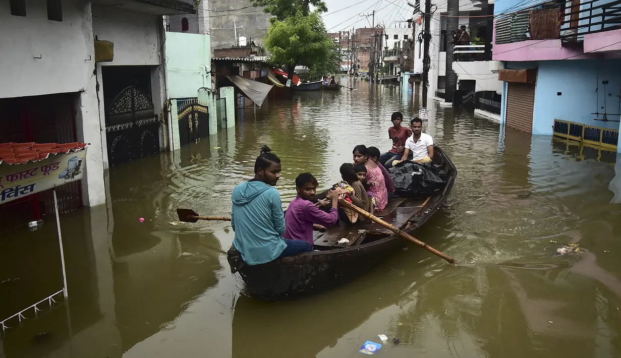 Warga menaiki perahu saat melintasi jalan yang terendam banjir di Chhota Baghara, Allahabad, India, Rabu (11/8/2021). Hujan lebat menyebabkan banjir di Allahabad. (SANJAY KANOJIA/AFP)