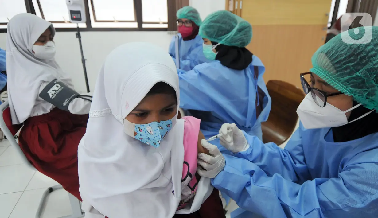 Petugas kesehatan menyuntikkan vaksin COVID-19 kepada siswa di SDN 02 Ciater, Tangerang Selatan, Selasa (14/12/2021). Mulai Hari ini, 11 provinsi di Indonesia secara serentak melaksanakan vaksinasi COVID-19 dengan sasaran anak berusia 6 hingga 11 tahun. (merdeka.com/Arie Basuki)