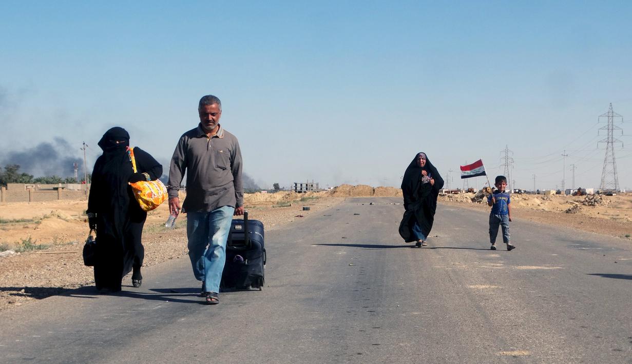 Sejumlah Warga  melarikan diri dari rumah mereka karena bentrokan antara pasukan keamanan Irak dengan militas ISIS di kota Hit, provinsi Anbar, (5/4/2016). (REUTERS/Stringer)