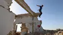 Seorang pemuda Suriah melakukan parkour di atas reruntuhan bangunan yang hancur akibat serangan pasukan rezim di kota Binnish di provinsi barat laut Idlib pada 17 Juni 2020. Parkour merupakan olahraga ketangkasan yang terdiri dari lari, melompat, salto dan berayun. (Abdulaziz KETAZ / AFP)