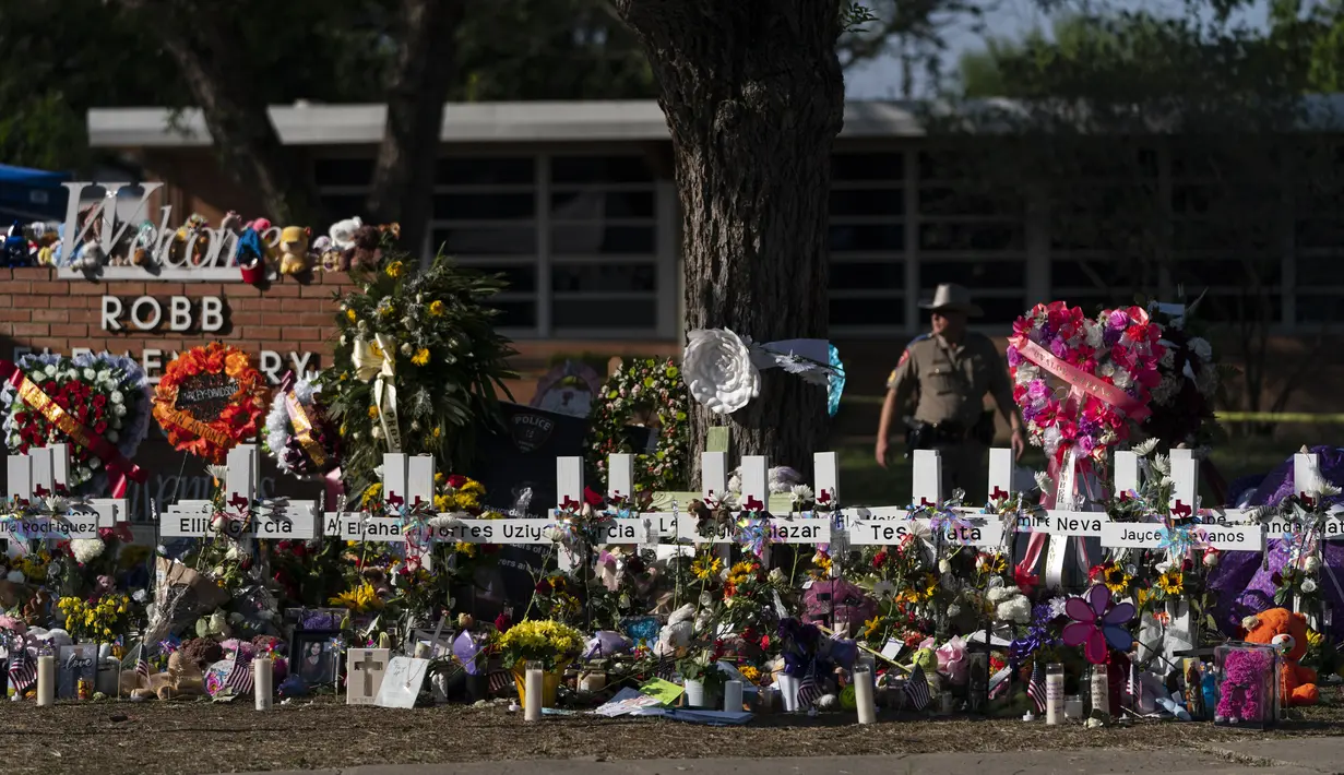 Bunga dan lilin ditempatkan sekitar salib dalam sebuah peringatan di luar Robb Elementary School untuk menghormati para korban yang tewas dalam penembakan sekolah pekan ini di Uvalde, Texas, Amerika Serikat, 28 Mei 2022. (AP Photo/Jae C. Hong)