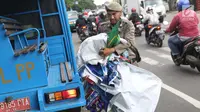 Petugas Satpol PP membawa APK usai diturunkan dari pagar pembatas di Jalan Raya Bogor dekat GOR Ciracas, Jakarta, Rabu (23/1). Penurunan APK ini karena pemasangannya dianggap melanggar ketentuan. (Liputan6.com/Helmi Fithriansyah)