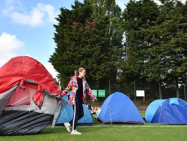 Dua wanita memindahkan tenda mereka ketika mengantre untuk membeli tiket pada hari pertama turnamen tenis Kejuaraan Wimbledon 2019 di The All England Tennis Club di Wimbledon, London barat daya (1/7/2019). Turnamen ini dimulai 1 Juli-14 Juli 2019. (AFP Photo/Ben Stansall)