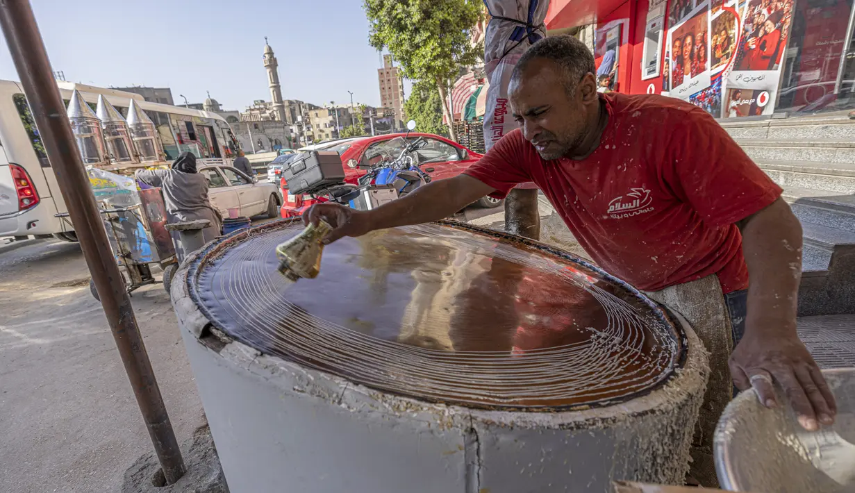 Pembuat penganan Mesir Mostafa Anwar membuat makanan penutup tradisional yang disebut "Kunafa" pada bulan Ramadhan, di kiosnya di ibu kota Kairo, 14 April 2022.  Kunafa terbuat dari adonan pastry mirip bihun, kemudian diisi dengan isian kacang, lalu dipanggang. (Khaled DESOUKI/AFP)