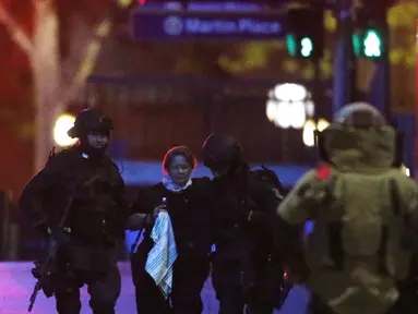 Dua petugas polisi bersenjata lengkap membantu sandera dari Kafe Lindt, Martin Place, Sydney (16/12/2014). (REUTERS/Jason Reed)