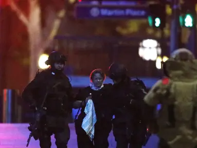 Dua petugas polisi bersenjata lengkap membantu sandera dari Kafe Lindt, Martin Place, Sydney (16/12/2014). (REUTERS/Jason Reed)