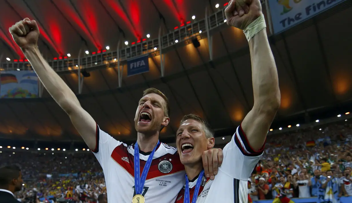 Per Mertesacker (kiri) berangkulan dengan Bastian Schweinsteiger merayakan kemenangan Jerman di Piala Dunia 2014 sekaligus mencetak sejarah sebagai tim Eropa pertama yang menang di Amerika Latin, (14/7/2014). (REUTERS/Eddie Keogh)