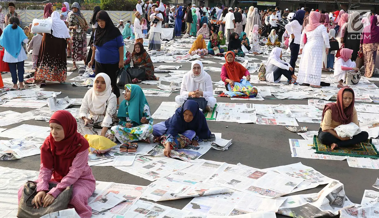 Sejumlah jamaah usai melaksanakan salat id Hari Raya Idul Fitri 1 Syawal 1439 H di kawasan Senen, Jakarta, Jumat (15/6). Banyaknya koran yang berserakan membuat petugas harus sigap membersihkan agar tidak mengotori jalan. (Liputan6.com/Immanuel Antonius)
