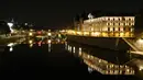 Pandangan umum jembatan Pont au Change dan pengadilan tertinggi Paris tercermin di sungai Seine pada malam hari selama penerapan lockdown atau penguncian wilayah di Paris, 23 April 2020. Pandemi corona COVID-19 membuat Prancis menerapkan lockdown. (Ludovic MARIN / AFP)