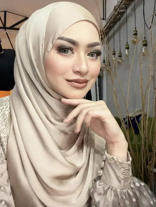Nathalie nampak glamor dengan riasan mata shimmernya dan lipstik cokelat serasi dengan pakaian dan hijab yang dikenakan. Credit: Instagram (@nathalieholscher)