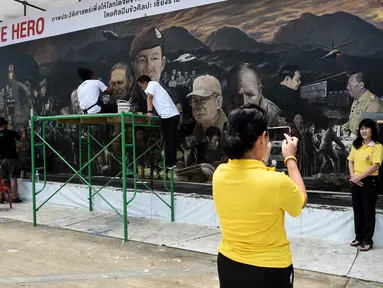 Pengunjung berfoto depan mural raksasa berjudul 'The Heroes' di Chiang Rai, Thailand, 18 Juli 2018. Mural itu untuk menghormati upaya penyelamatan 12 remaja dan pelatih sepak bola yang terperangkap di  gua lebih dari dua minggu. (AFP/Lillian SUWANRUMPHA)