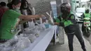 Pengemudi ojek online menerima nasi bungkus gratis di Kompleks Sinar Pamulang Permai, Pamulang Barat, Tangsel, Senin (13/4/2020). Nasi bungkus gratis ini bentuk kepedulian terhadap mereka yang berpenghasilan rendah dan terdampak perekonomiannya karena penyebaran Covid-19. (merdeka.com/Arie Basuki)