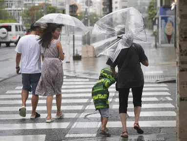 Orang-orang menyusuri jalan tempat wisata yang terkenal "Kokusai-dori" saat badai tropis mendekat di Naha, Pulau Okinawa, Jepang, Kamis (1/6/2023). (AP Photo/Hiro Komae)