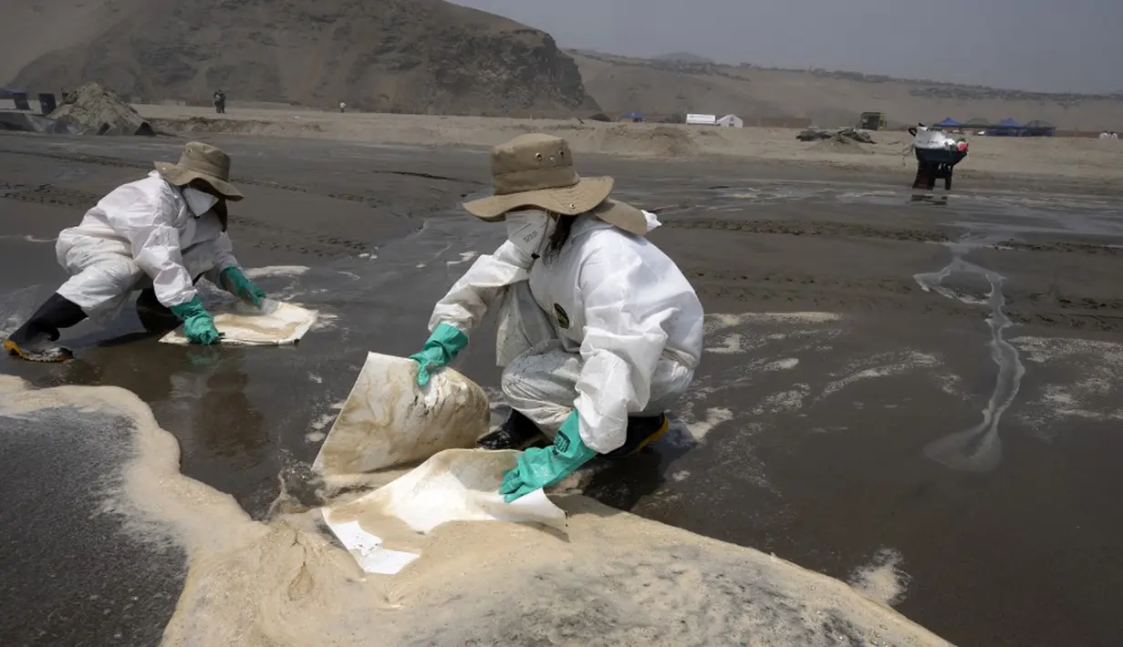 Petugas kebersihan bekerja untuk mengeluarkan minyak dari Pantai Cavero di Callao, Peru, 26 Januari 2022. Pembersihan Pantai Cavero dari tumpahan minyak kapal tanker Mare Doricum yang dihantam gelombang akibat letusan gunung berapi Tonga masih terus dilakukan. (Cris BOURONCLE/AFP)