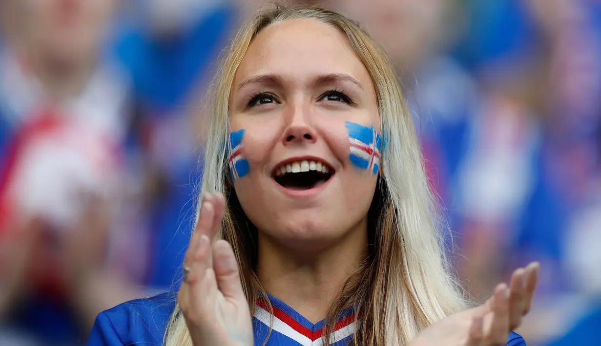 Suporter cantik timnas Islandia mengecat pipinya dengan gambar bendera negaranya saat mendukung tim nasional Islandia melawan timnas Perancis dalam Perempat Final Piala Eropa 2016 di Stade de France, Prancis, (3/7).  (Reuters/John Sibley)