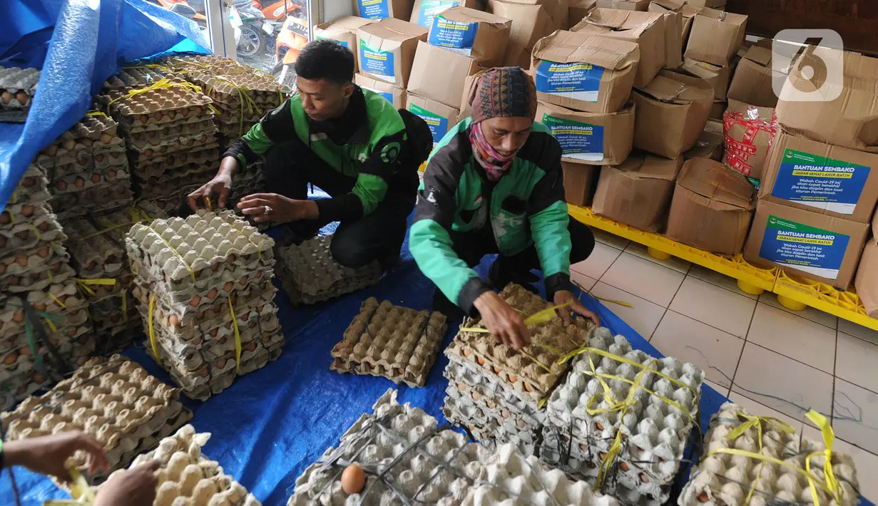 Pengemudi ojek online mengemas bansos untuk warga yang terdampak COVID-19 di Kantor Pos, Cibinong, Bogor, Jawa Barat, Senin (20/4/2020). Pemprov Jabar menyalurkan bansos senilai Rp 500 ribu bagi warga berpenghasilan rendah dan termasuk miskin baru akibat pandemi COVID-19. (merdeka.com/Arie Basuki)