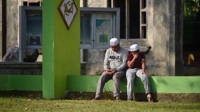 Orang-orang berdoa saat ziarah di Kuburan Massal Ulee Lheue selama peringatan 14 tahun tsunami Aceh di Banda Aceh, Rabu (26/12). Sejumlah warga mengenang keluarga yang meninggal akibat bencana tsunami di Aceh 14 tahun silam. (Chaideer MAHYUDDIN / AFP)