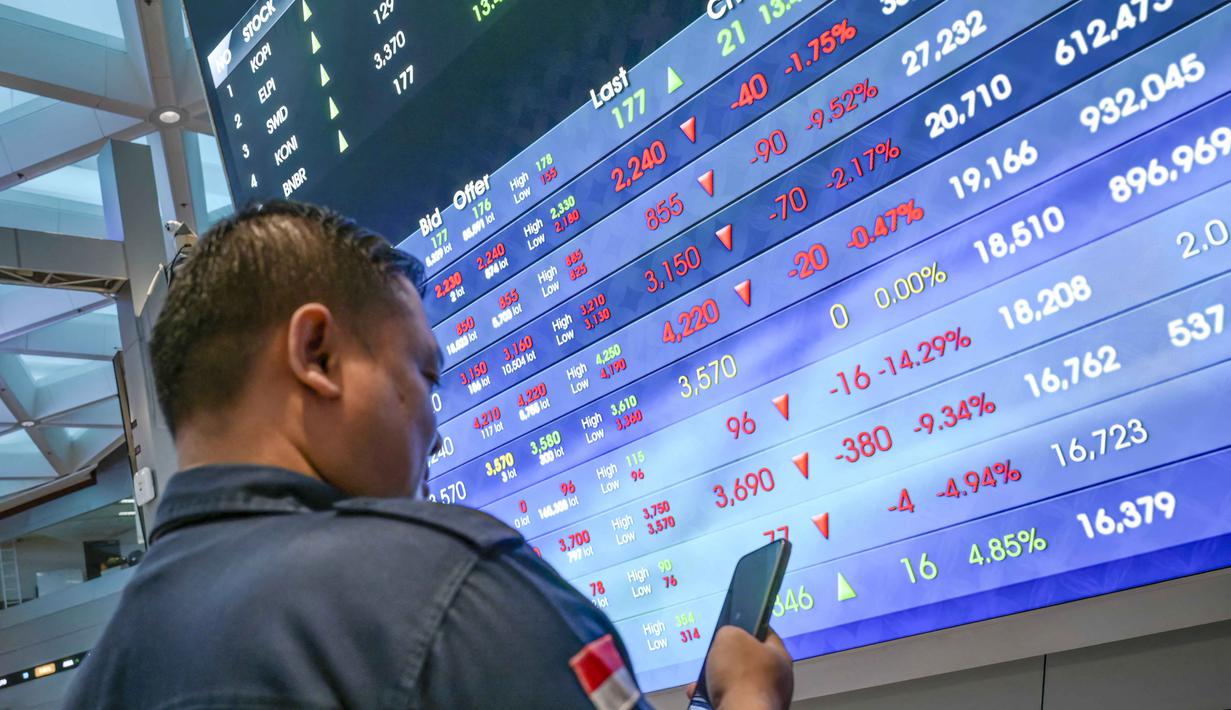 Seorang pria melihat ponselnya di depan layar yang menampilkan Indeks Harga Saham Gabungan (IHSG), yang anjlok signifikan selama pembukaan pasar, di gedung Bursa Efek Indonesia di Jakarta pada Rabu 13 Mei 2026. (BAY ISMOYO/AFP)