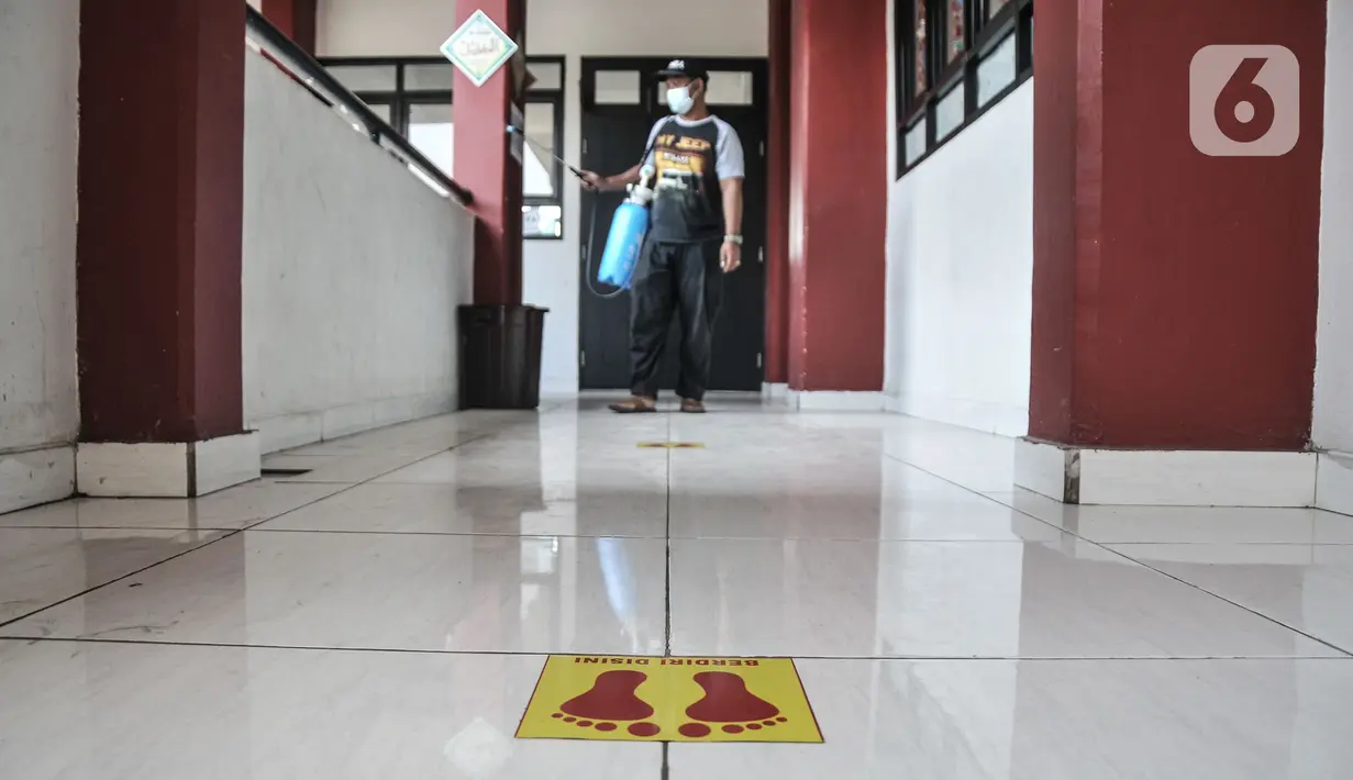 Petugas melintasi stiker tanda jaga jarak di lantai SD Negeri Malaka Jaya 07 Pagi, Jakarta, Kamis (26/8/2021). Pemprov DKI berencana membuka kembali sekolah untuk pembelajaran tatap muka terbatas pada Senin (30/8) setelah status PPKM turun ke level 3. (merdeka.com/Iqbal S Nugroho)