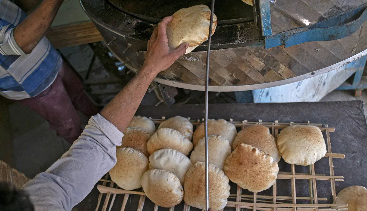 Pria Mesir bekerja di sebuah toko roti di sebuah pasar di Kairo, pada 17 Maret 2022. Melonjaknya harga roti yang dipicu oleh invasi Rusia ke Ukraina telah menggigit daya beli konsumen di Mesir, importir gandum terkemuka dari negara-negara bekas Soviet. (Khaled DESOUKI / AFP)