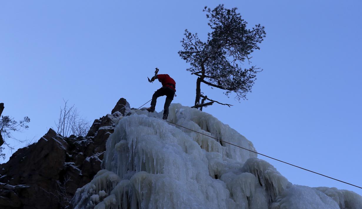 Seorang pria menuruni dinding es buatan di desa Vir, Republik Ceko, Minggu (14/2/2021). Ketika suhu turun di Republik Ceko, pemanjat tebing memanfaatkan kondisi beku dengan mengubah permukaan batu menjadi dinding es setinggi 20 meter untuk pendaki. (AP Photo/Petr David Josek)