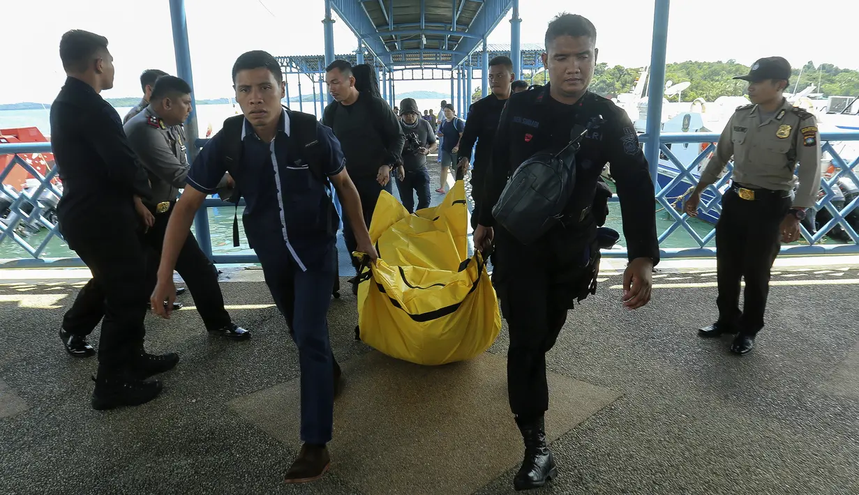 Anggota kepolisian mengangkat kantong jenazah yang berisikan puing-puing dan barang-barang dari jatuhnya pesawat jenis M-28 Skytrcuk milik Polri yang membawa 13 penumpang, di Pelabuhan Telaga Punggur, Batam, Kepulauan Riau, Minggu (4/12). (SEI RATIFA/AFP)