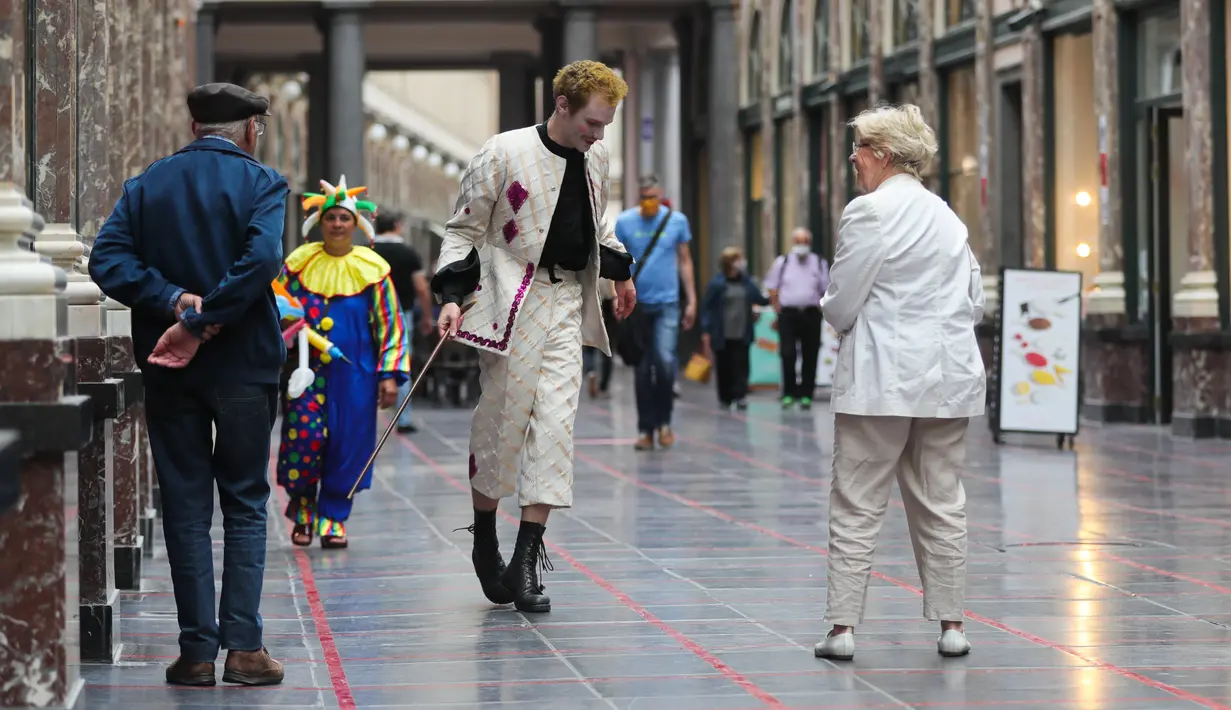 Seorang seniman memainkan permainan dalam garis persegi (grid game) dengan pelintas di Royal Gallery of Saint Hubert di Brussel, Belgia (15/7/2020). Permainan ini dirancang agar orang menghormati aturan jaga jarak sosial selama pandemi COVID-19. (Xinhua/Zheng Huansong)