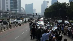 Warga mengambil gambar iring-iringan mobil jenazah yang membawa almarhum Presiden ke-3 RI, BJ Habibie saat melintasi Jalan Gatot Subroto menuju TMP Kalibata, Jakarta, Kamis (12/9/2019). BJ Habibie meninggal pada Rabu (11/9/2019) setelah menjalani perawatan di RSPAD. (Liputan6.com/Johan Tallo)