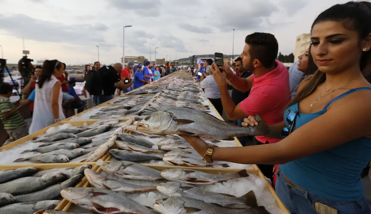 Seorang anggota Lebanon's Batroun Traders Association memegang ikan yang berhasil memecahkan rekor makanan laut terbanyak di daerah kota pantai Batroun, Minggu (4/9). Menurut panitia, total ikan yang dikumpul sebanyak 2 ton 614 kg. (AFP PHOTO/Anwar AMRO)