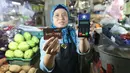 Pedagang menunjukkan kartu E-Money dan mesin Q Cash di PD Pasar Jaya  Mayestik, Jakarta, Rabu (4/4). Program pembayaran ini merupakan bentuk dukungan pada gerakan nasional non tunai. (Liputan6.com/Angga Yuniar)