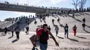Sekelompok migran berlari di sepanjang sungai kering Sungai Tijuana dalam upaya untuk sampai ke pelabuhan masuk El Chaparral, di Tijuana, Baja California State, Meksiko, dekat perbatasan AS-Meksiko (25/11). AFP Photo/Guillermo Arias)