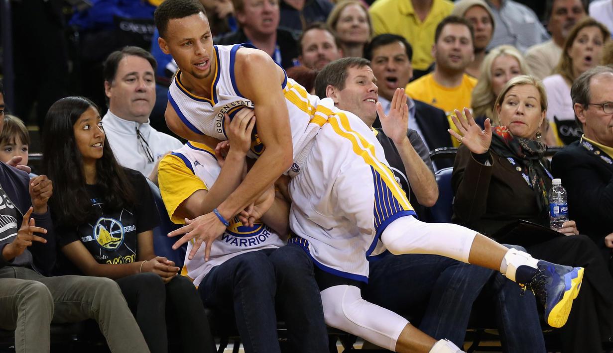 Stephen Curry #30 terjatuh menindih fans Golden State Warriors lsaat melawan Portland Trail Blazers  pada laga NBA Playoffs di ORACLE Arena,Oakland, California,(3/4/2016). (Ezra Shaw/Getty Images/AFP)