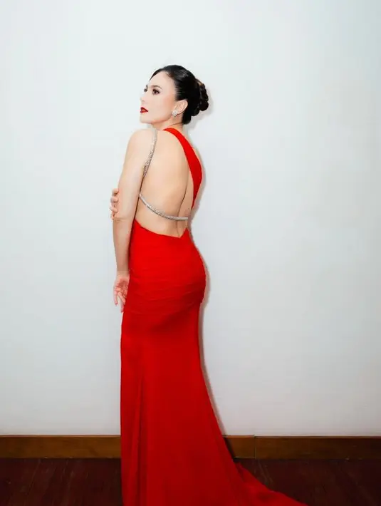 Dress merah panjang menyapu lantai tersebut yang dibuat oleh desainer Jan Handrianto ini memiliki aksen tali berwarna silver. Senada dengan aksesori anting yang ia kenakan. [@wulanguritno]