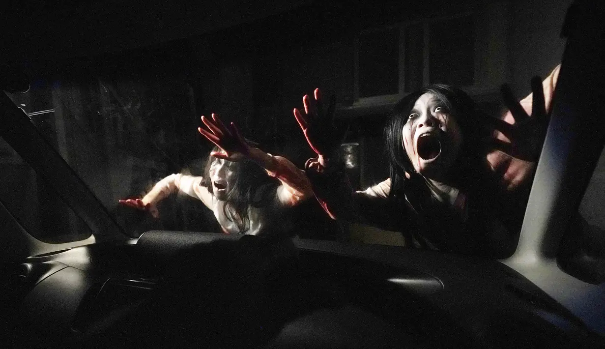 Para pemeran zombie tampil dekat kaca kendaraan saat demonstrasi pertunjukan rumah hantu drive-in di Tokyo, Jepang, Selasa (18/8/2020). Rumah hantu drive-in ini diadakan di tengah pandemi COVID-19. (AP Photo/Eugene Hoshiko)