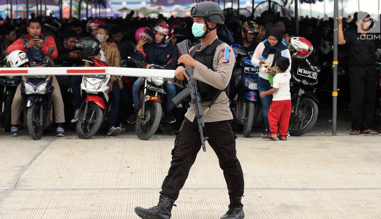 Polisi melintas di depan antrean pemudik bermotor yang akan masuk ke dalam kapal penyeberangan di Pelabuhan Merak, Banten, Jumat (23/6). H-2 Lebaran 2017, ribuan pemudik bermotor memadati dermaga 6 Pelabuhan Banten. (Liputan6.com/Helmi Fithriansyah)
