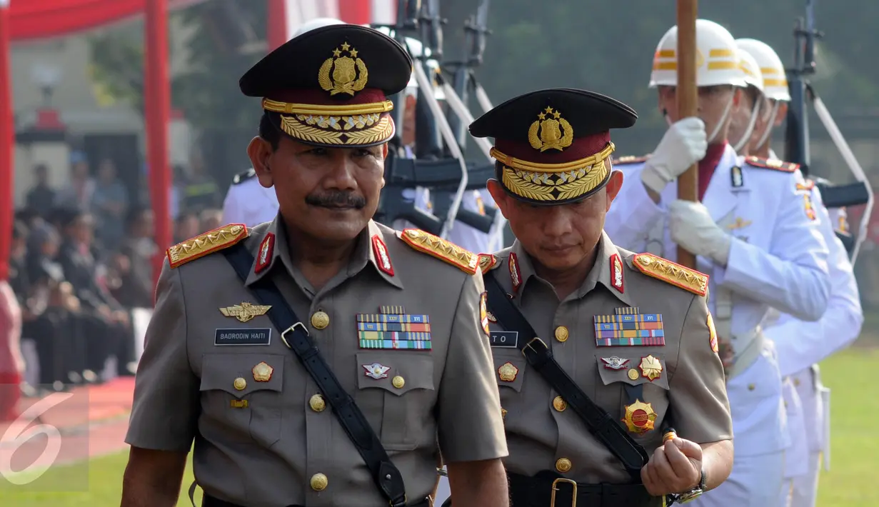 Jenderal Badrodin Haiti bersama Jenderal Tito Karnavian berjalan menuju mimbar upacara sertijab Kapolri di Stadion PTIK, Jakarta, Kamis (14/7). Badrodin Haiti resmi menyerahkan tongkat komando Kapolri kepada Tito Karnavian. (Liputan6.com/Helmi Afandi)