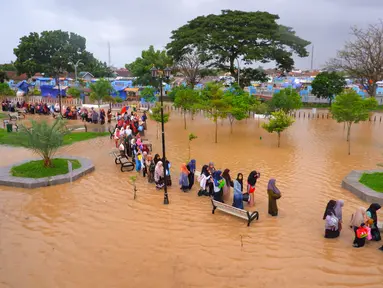 Warga mengarungi banjir saat mengungsi pasca banjir di Serang, Provinsi Banten (1/3/2022).  Banjir merendam Kota Serang akibat hujan deras yang turun sejak Senin malam (28/2/2022) hingga hari ini. (AFP/Dziki Oktomauliyadi)