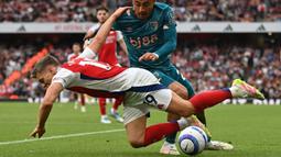 Pemain Arsenal, Leandro Trossard (kiri) terjatuh saat berebut bola dengan pemain Bournemouth, Julian Araujo dalam laga lanjutan Liga Inggris 2024/2025 di Emirates Stadium, London, Inggris, Sabtu (03/05/2025) waktu setempat. (AFP/Glyn Kirk)