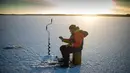 Seorang pria memasukan umpan ikan saat memancing di laut Bothnia yang sedang membeku, Vaasa, Finlandia (29/12). Suhu yang sangat ekstrem, pemancing dapat melakukan aksinya di tengah laut dengan berjalan kaki. (AFP PHOTO/Olivier Morin)