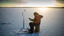 Seorang pria memasukan umpan ikan saat memancing di laut Bothnia yang sedang membeku, Vaasa, Finlandia (29/12). Suhu yang sangat ekstrem, pemancing dapat melakukan aksinya di tengah laut dengan berjalan kaki. (AFP PHOTO/Olivier Morin)