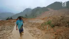 Warga melintas di atas perkampungan yang tertimbun longsor di Dusun Cimapag, Desa Sirnaresmi, Kecamatan Cisolok, Sukabumi, Selasa (1/1). BNPB mencatat, sebanyak 41 orang diduga masih tertimbun longsoran. (merdeka.com/Arie Basuki)
